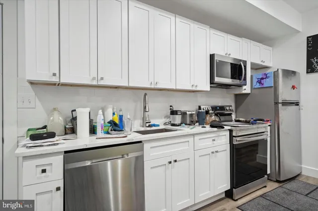 a kitchen with stainless steel appliances granite countertop white cabinets sink and a stove