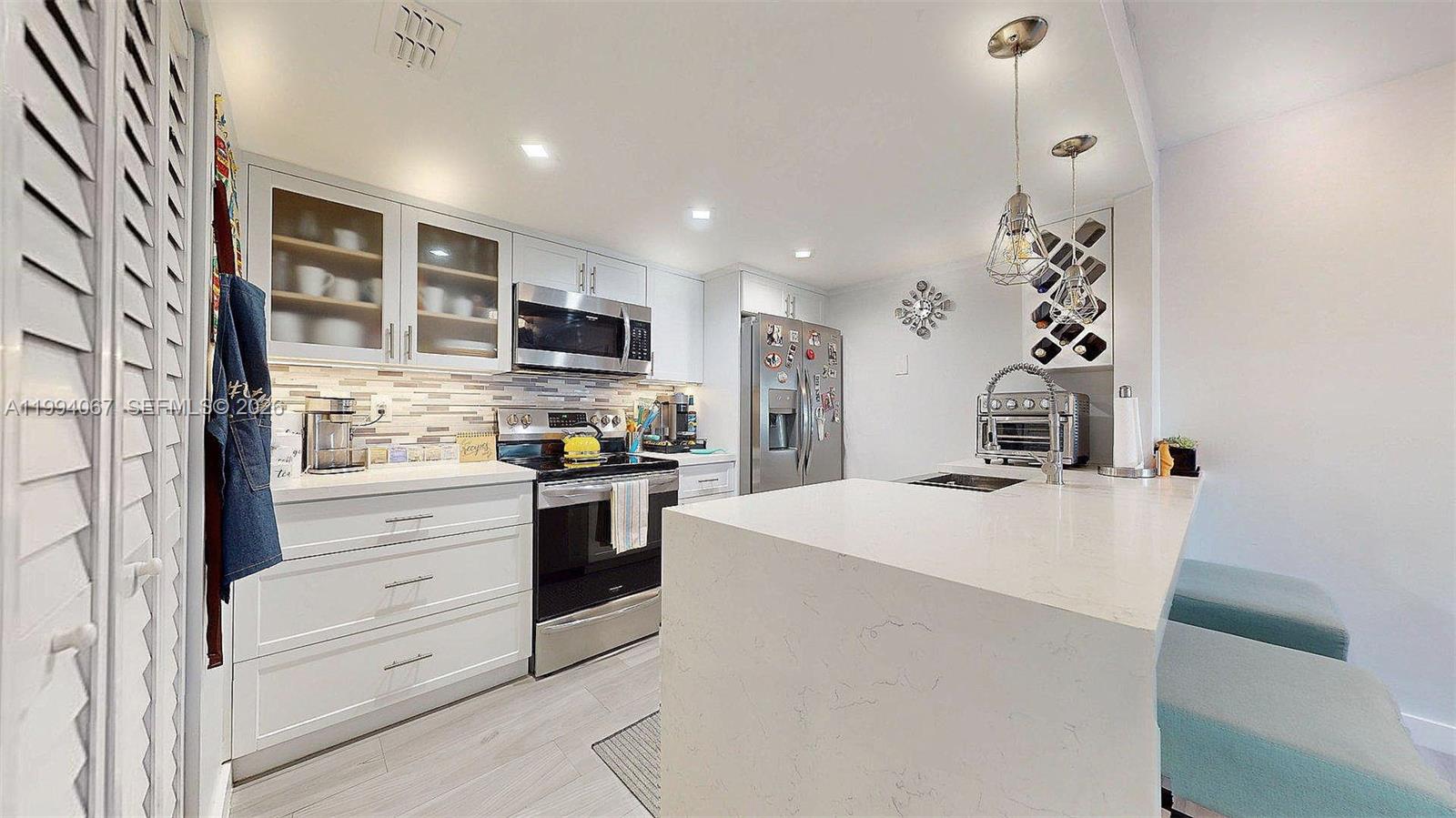 6840 Southwest 45th Lane, Unit 5 Miami, FL 33155 - Photo 14 of 34 a kitchen with kitchen island a stove a sink and a refrigerator