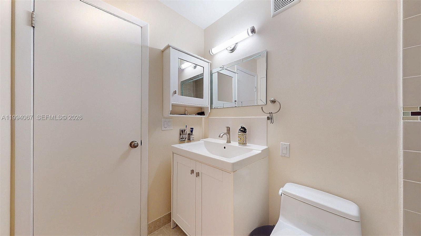 6840 Southwest 45th Lane, Unit 5 Miami, FL 33155 - Photo 29 of 34 a bathroom with a toilet a sink and mirror