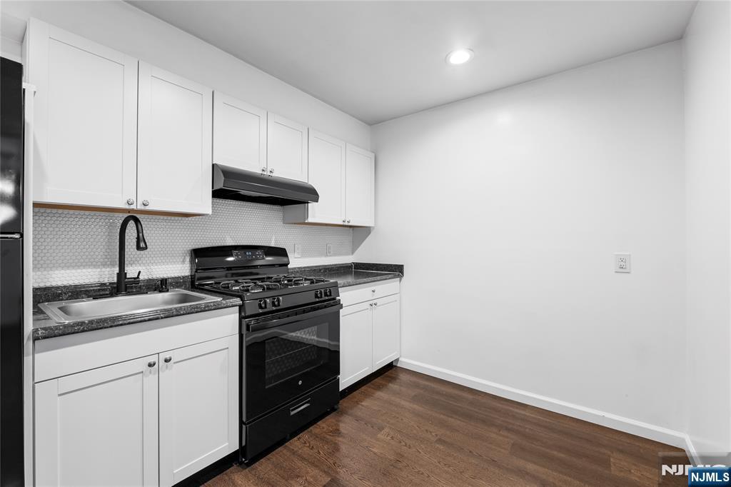 335 Paterson Avenue, Unit F East Rutherford, NJ 07073 - Photo 5 of 12 a kitchen with granite countertop white cabinets and stainless steel appliances