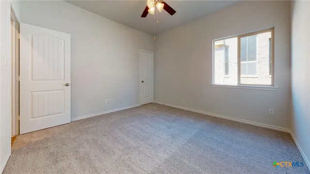 an empty room with chandelier fan and windows