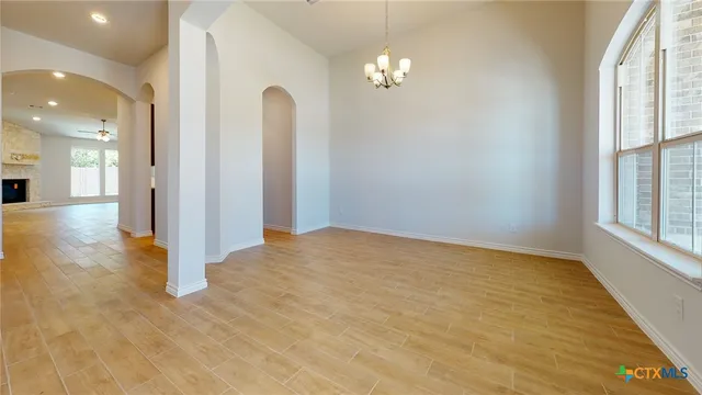 an empty room with chandelier fan and windows