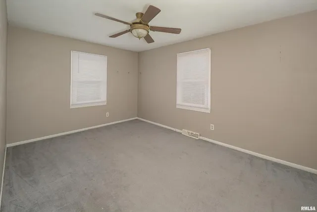 an empty room with a window and a fan