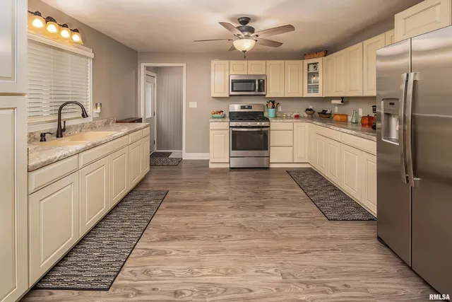 a large kitchen with cabinets a sink and stainless steel appliances
