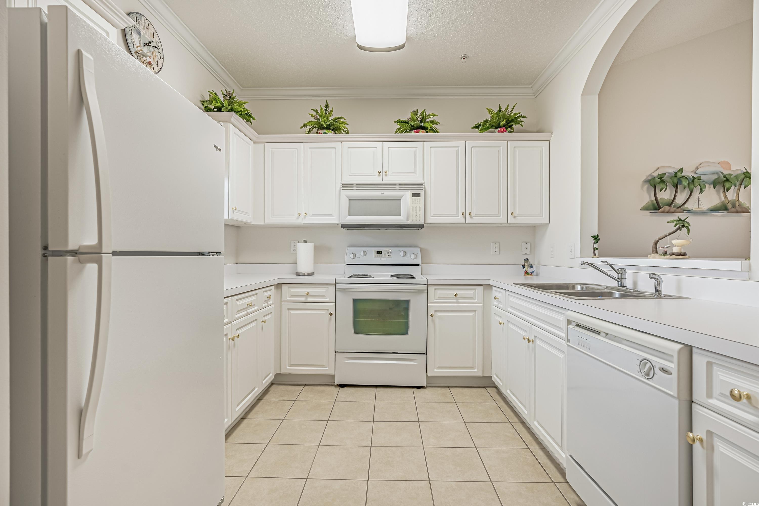 500 Wickham Drive, Unit HEATHERSTONE BUILDING 12 Myrtle Beach, SC 29579 - Photo 12 of 32 Kitchen featuring white appliances, crown molding, light tile patterned floors, light countertops, and white cabinetry
