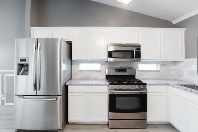 a kitchen with stainless steel appliances a stove top oven a sink dishwasher and a refrigerator with wooden floor