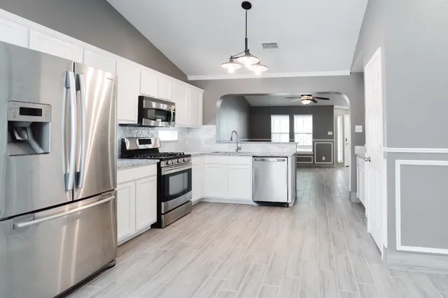a kitchen with a sink cabinets stainless steel appliances and a window