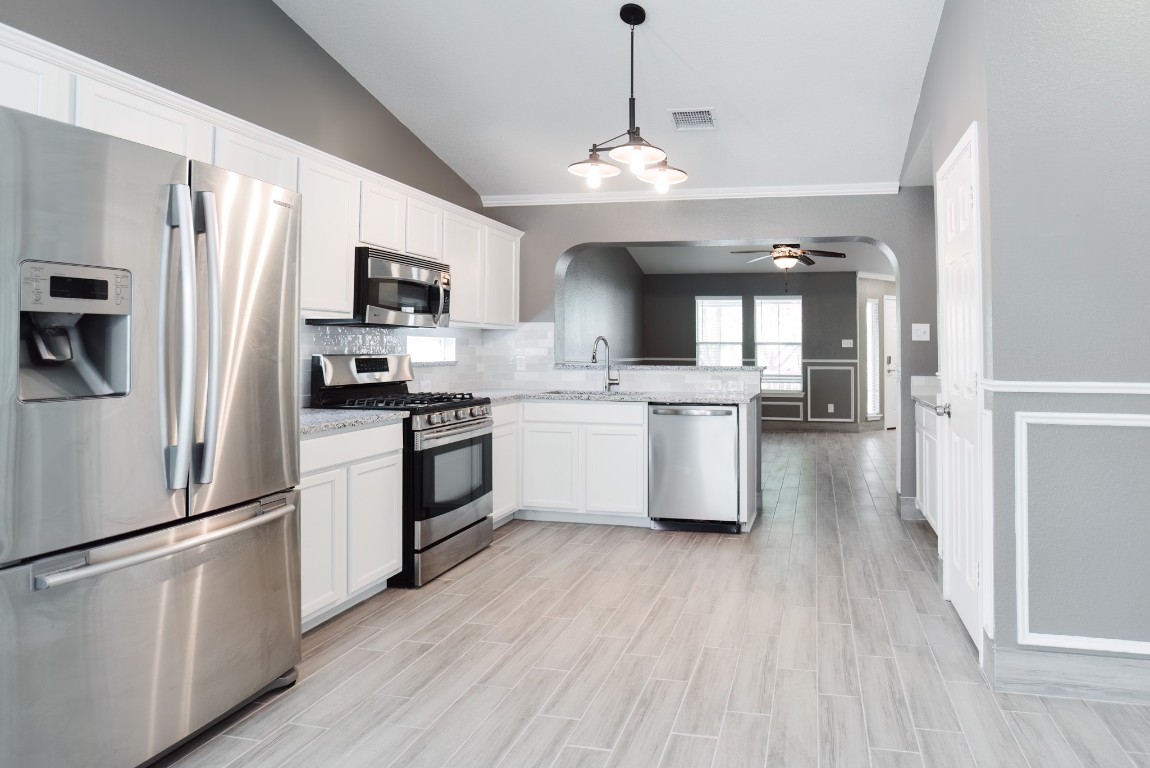 692 Scheel Kyle, TX 78640 - Photo 18 of 34 a kitchen with stainless steel appliances granite countertop a refrigerator a sink dishwasher a stove and white countertops with wooden floor
