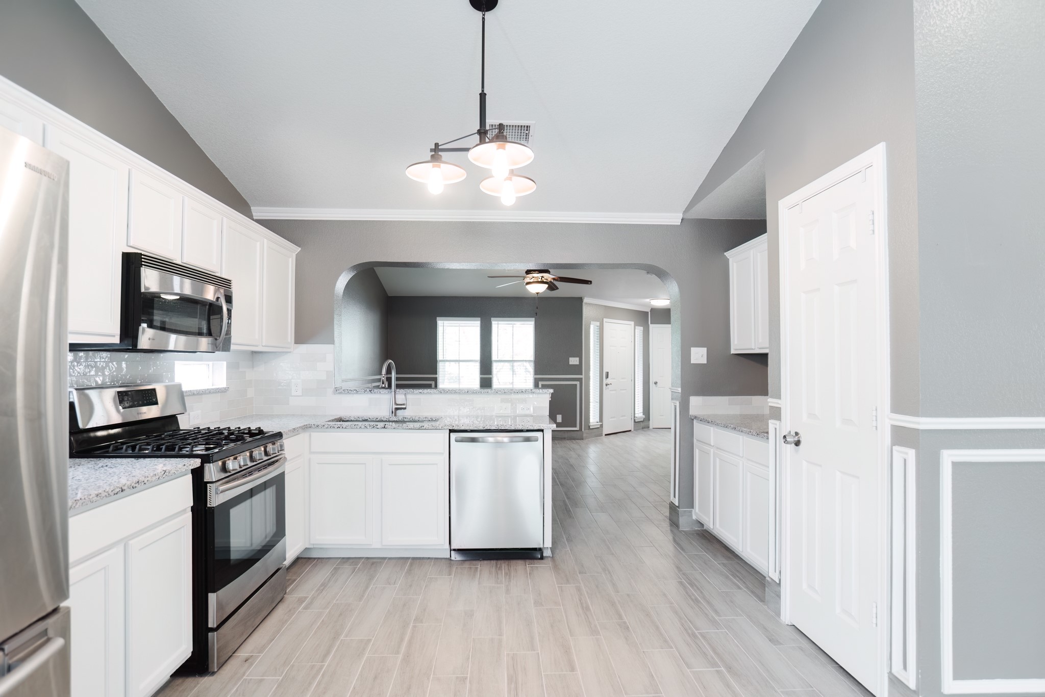 692 Scheel Kyle, TX 78640 - Photo 19 of 40 a kitchen with stainless steel appliances a stove top oven a sink dishwasher and a refrigerator with wooden floor