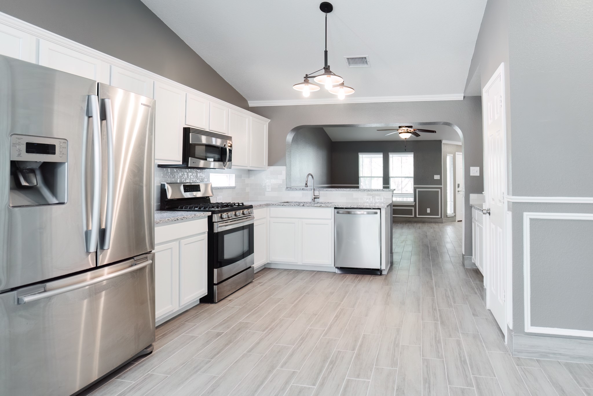 692 Scheel Kyle, TX 78640 - Photo 20 of 40 a kitchen with stainless steel appliances granite countertop a refrigerator a sink dishwasher a stove and white countertops with wooden floor