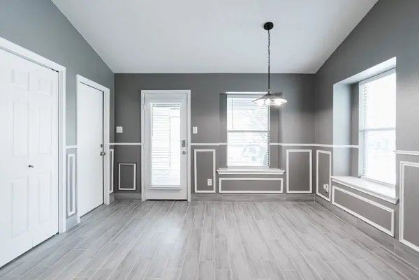 a view of an empty room with a window and wooden floor