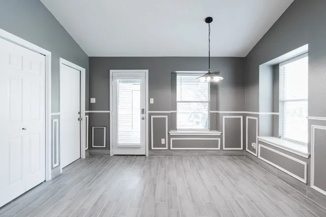 a view of an empty room with a window and wooden floor