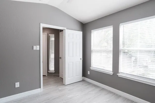 a view of an empty room with a window and wooden floor