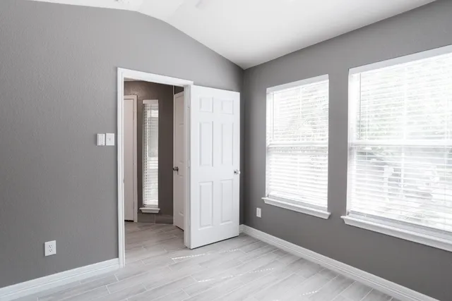a view of an empty room with a window and wooden floor