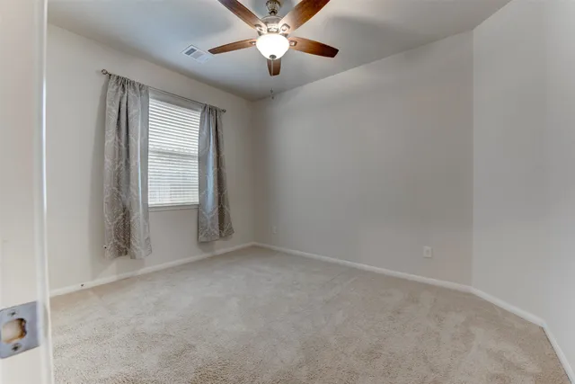 an empty room with windows and fan