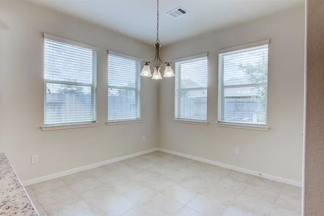 a view of an empty room with windows and chandelier