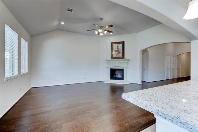 a view of a livingroom with a fireplace a ceiling fan and wooden floor