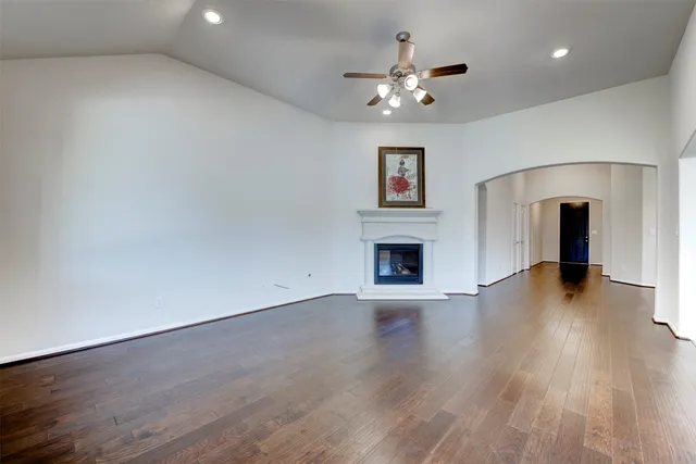 a view of an empty room with wooden floor and a fireplace
