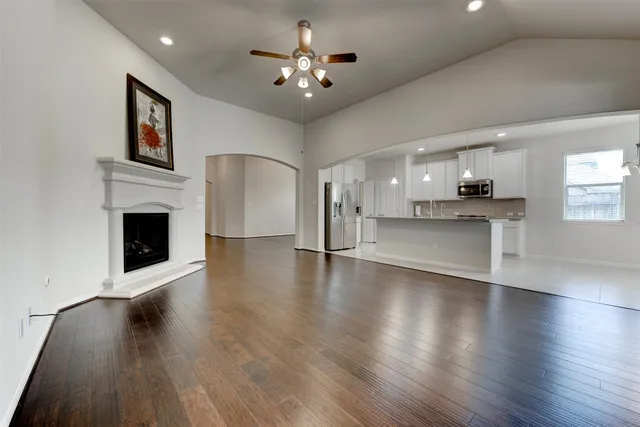 a view of a kitchen with furniture a ceiling fan and wooden floor
