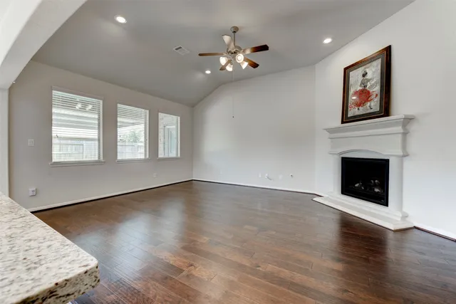 a view of an empty room with wooden floor and a fireplace