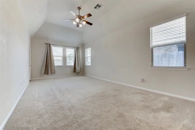 an empty room with chandelier fan and windows