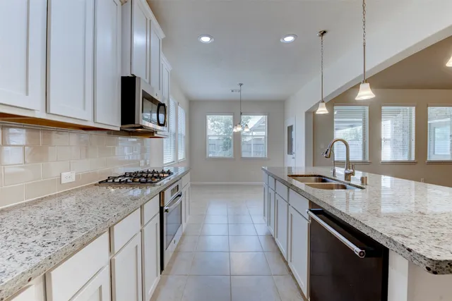 a kitchen with granite countertop stainless steel appliances a sink stove and cabinets