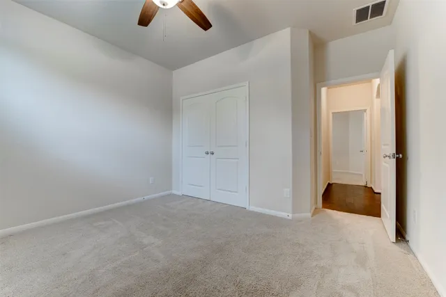 an empty room with closet and chandelier fan