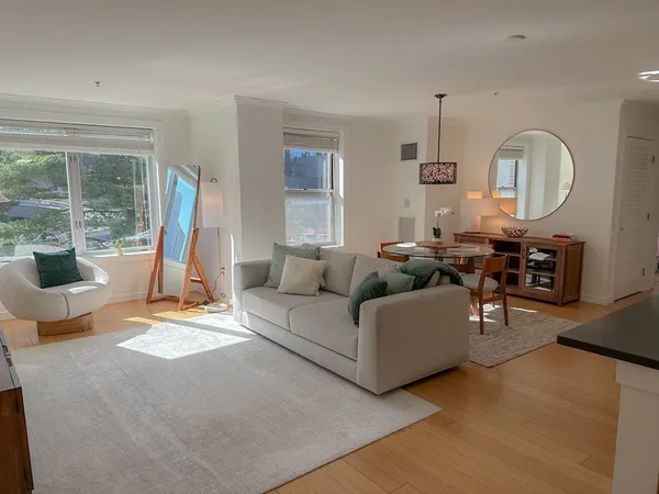 a living room with furniture a large window and wooden floor