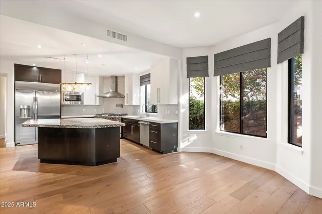 a large kitchen with stainless steel appliances granite countertop a large stove a sink dishwasher and a refrigerator with wooden floor