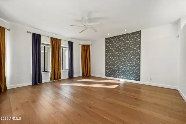 a view of an empty room with a window and wooden floor