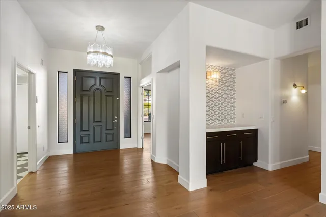 an empty room with wooden floor chandelier and windows