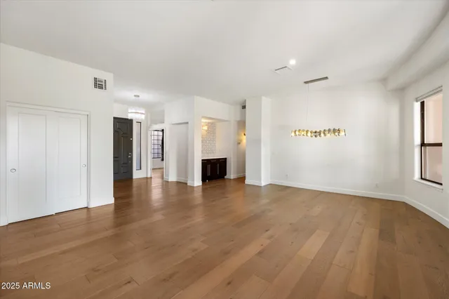 a view of an empty room with a window and a kitchen