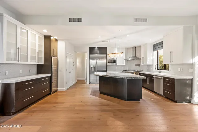 a large kitchen with stainless steel appliances granite countertop a stove refrigerator and a sink