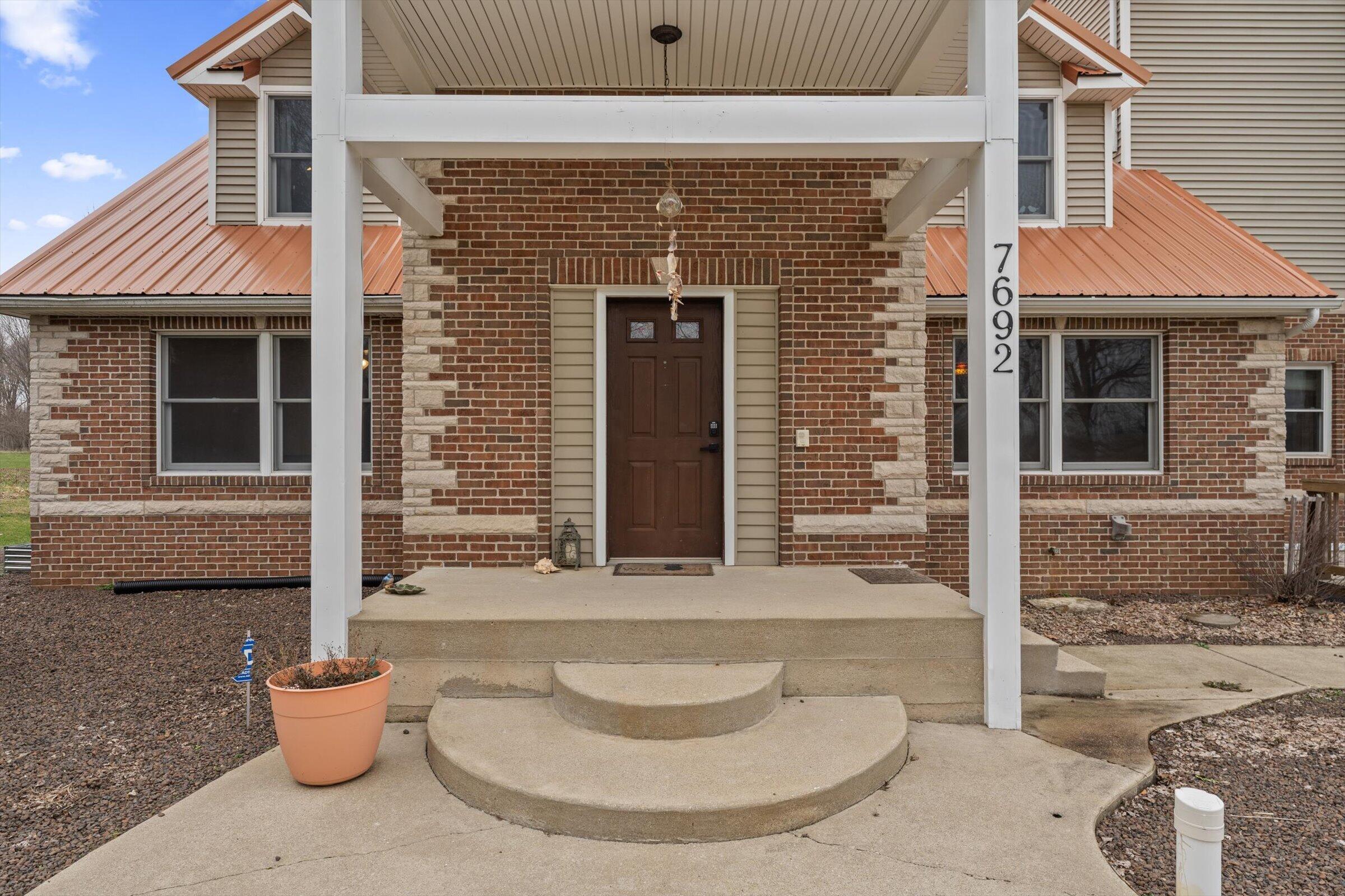 7692 North Emery Road Rolling Prairie, IN 46371 - Photo 2 of 69 a view of a brick house with potted plants