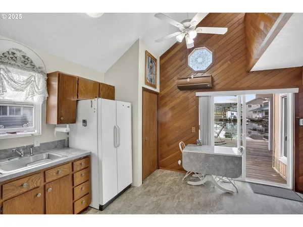 a kitchen with a refrigerator a stove a sink and a dining table with wooden cabinet