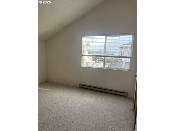 an empty room with a view of a livingroom with a large window