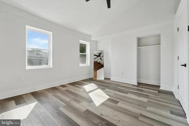a view of empty room with wooden floor and fan
