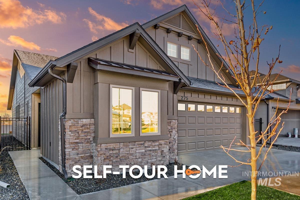 View of front of property featuring stone siding, board and batten siding, concrete driveway, and a garage