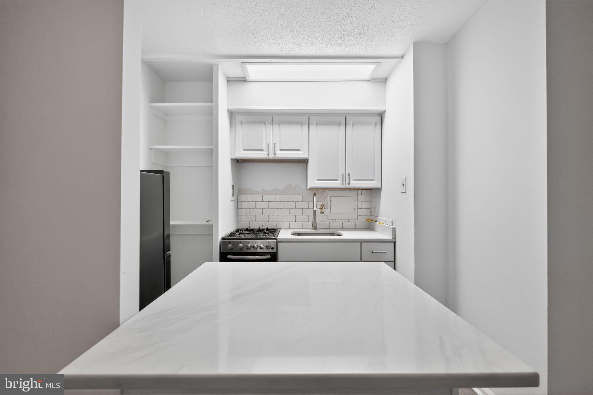 2101-17 Chestnut Street, Unit 1121 Philadelphia, PA 19103 - Photo 21 of 42 a kitchen with white cabinets and a stove