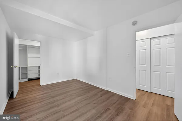 a view of an empty room with wooden floor and closet