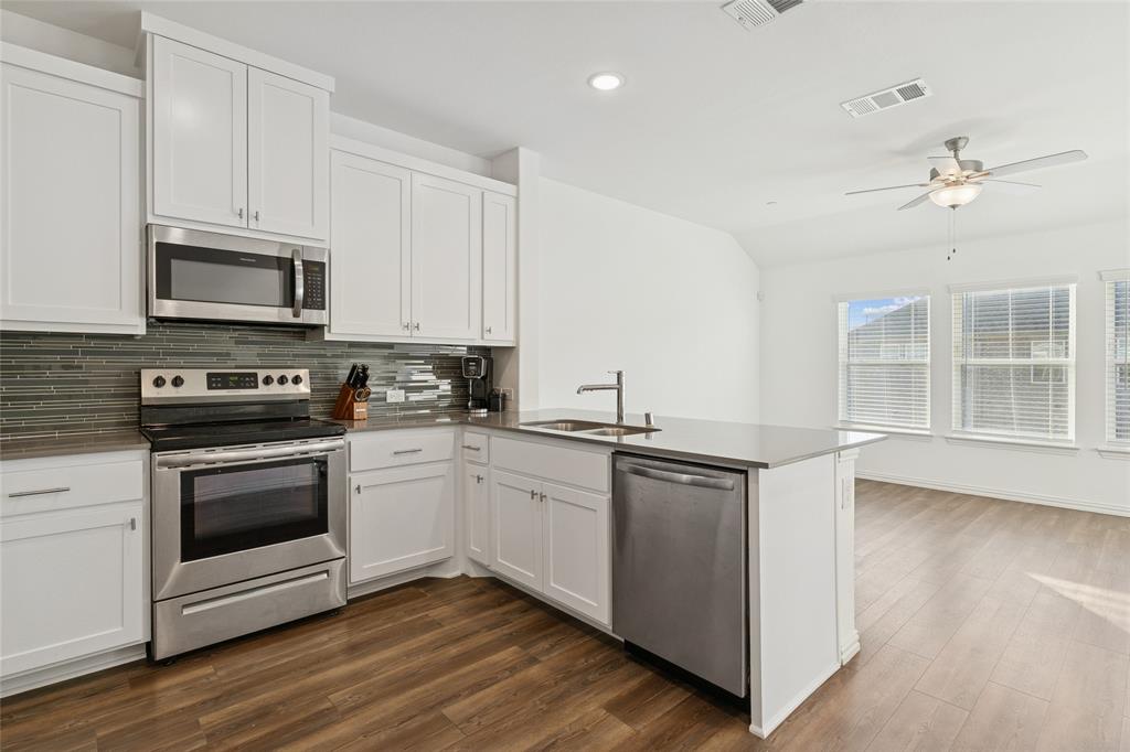 4703 Kindred Street Haltom City, TX 76117 - Photo 13 of 23 a kitchen with cabinets stainless steel appliances a sink and wooden floor