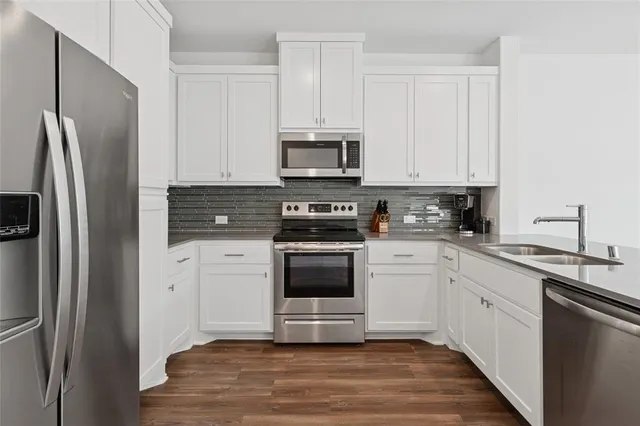 a kitchen with stainless steel appliances granite countertop a refrigerator stove a sink and white cabinets
