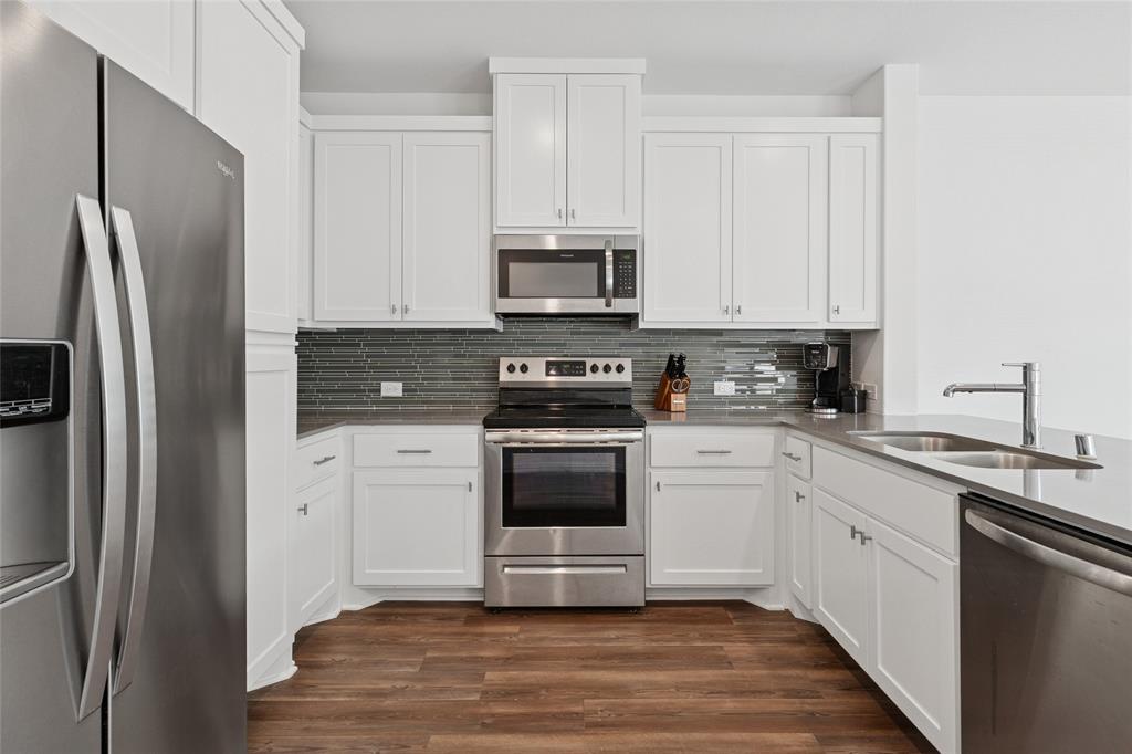 4703 Kindred Street Haltom City, TX 76117 - Photo 14 of 23 a kitchen with stainless steel appliances granite countertop a refrigerator stove a sink and white cabinets