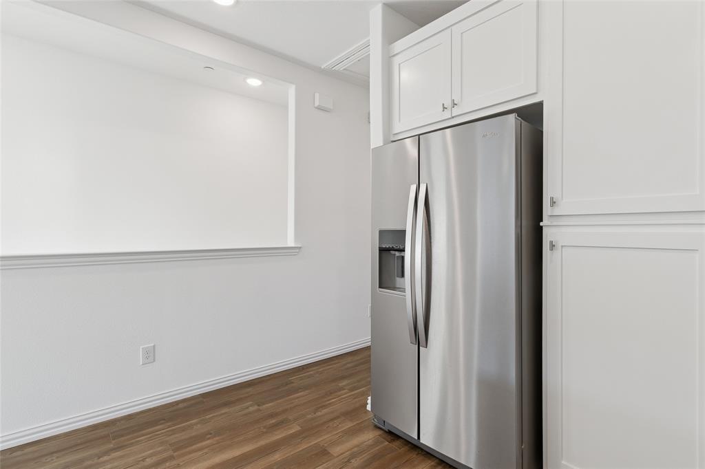4703 Kindred Street Haltom City, TX 76117 - Photo 16 of 23 an empty room with wooden floor and a refrigerator