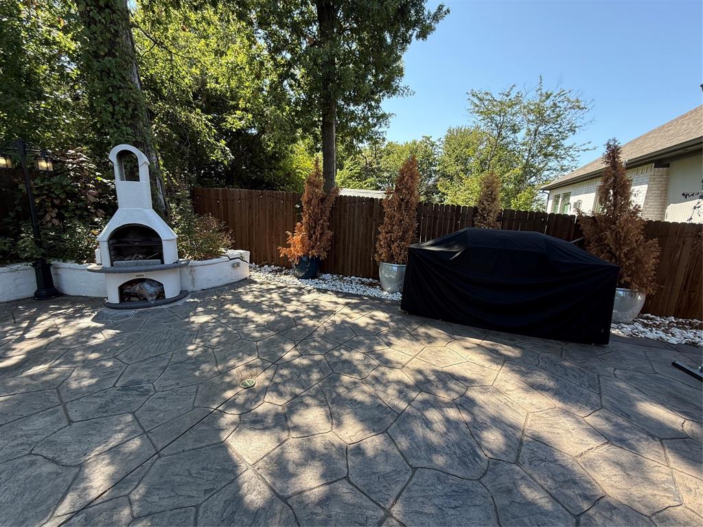 5212 Troupe Road McKinney, TX 75071 - Photo 30 of 38 Outdoor patio featuring stamped concrete flooring, a built-in stucco fireplace, a privacy fence, and white decorative stones