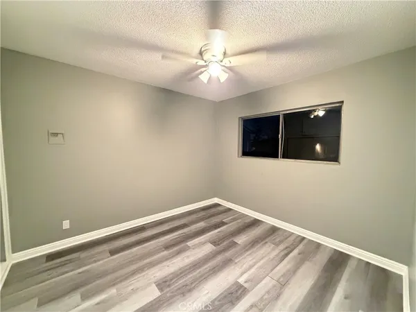 an empty room with wooden floor and fan