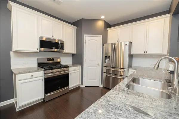 a kitchen with granite countertop a refrigerator stove and microwave