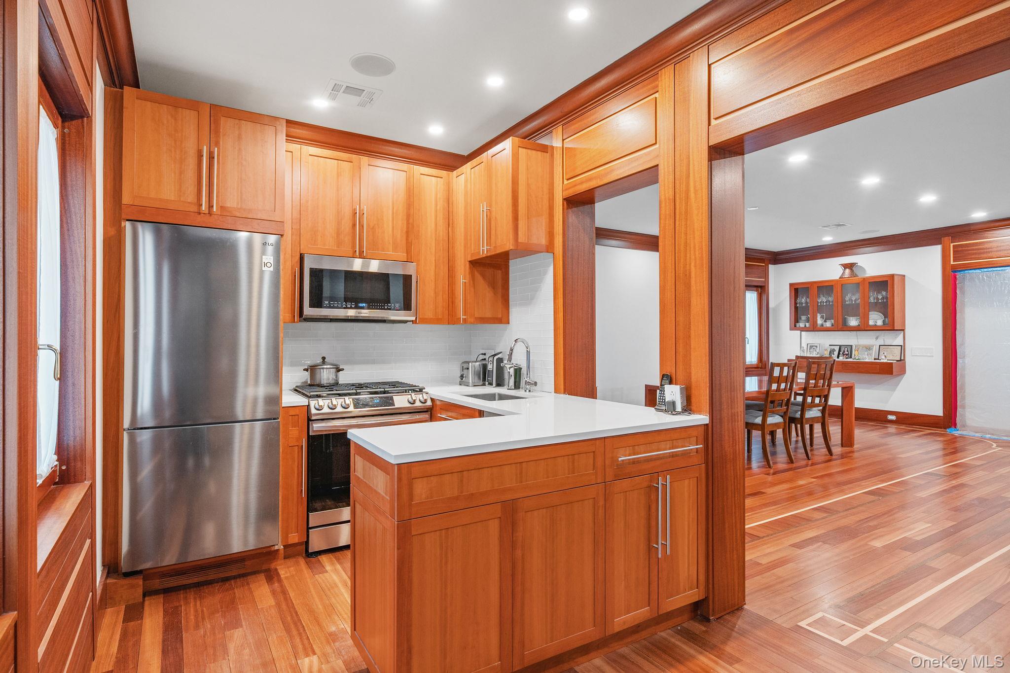 181 Walnut Street Lynbrook, NY 11563 - Photo 12 of 46 Kitchen with stainless steel appliances, light wood finished floors, decorative backsplash, recessed lighting, and brown cabinetry