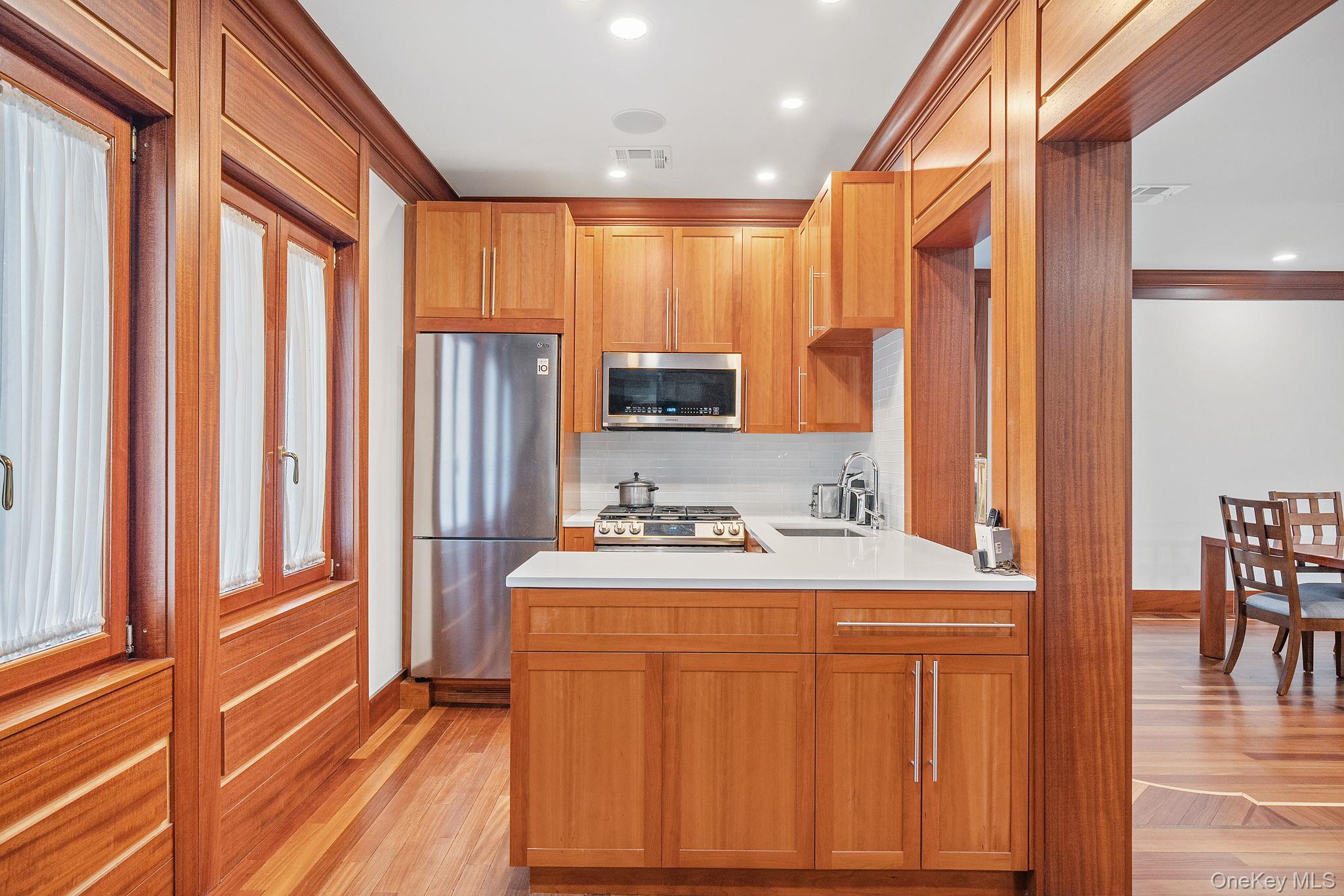 181 Walnut Street Lynbrook, NY 11563 - Photo 13 of 46 Kitchen featuring appliances with stainless steel finishes, light wood finished floors, tasteful backsplash, brown cabinets, and recessed lighting