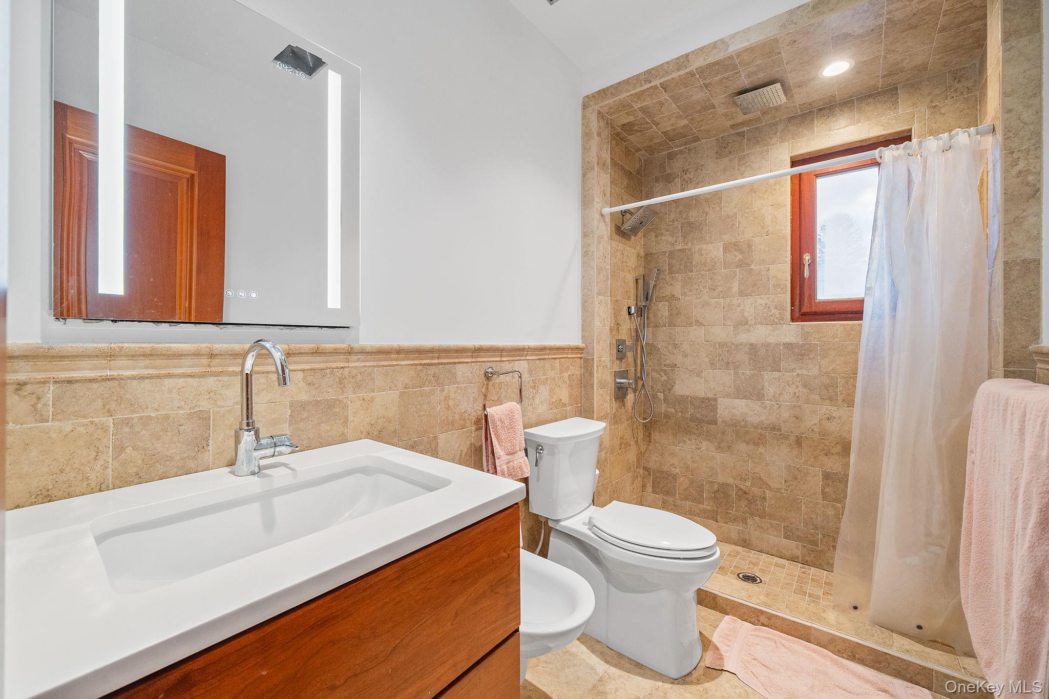 181 Walnut Street Lynbrook, NY 11563 - Photo 16 of 46 Bathroom featuring vanity, tile walls, a shower stall, a wainscoted wall, and a bidet